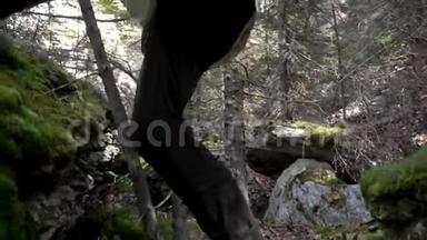 在一条山路上，近距离练习登山鞋。 录像。 接近男人的靴子和腿爬上岩石